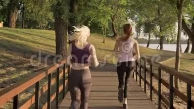 两位年轻漂亮的女跑步者在公园跨桥慢跑，<strong>减肥</strong>，健身<strong>模特</strong>跑步，从后面观看